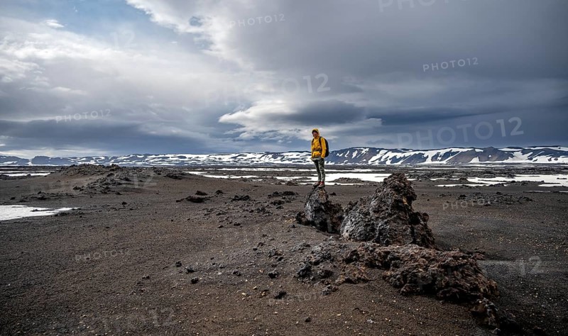 Hikers in snow-covered volcanic landscape with volcanic sand and petrified lava, crater of Askja volcano, Icelandic highlands, Iceland, Europe