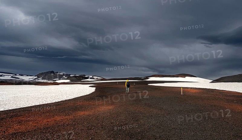 Hikers in snow-covered volcanic landscape with volcanic sand and petrified lava, crater of Askja volcano, Icelandic highlands, Iceland, Europe