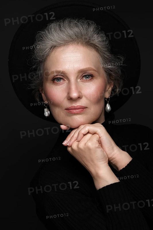 Portrait of a beautiful elderly woman in a white shirt with classic makeup and gray hair