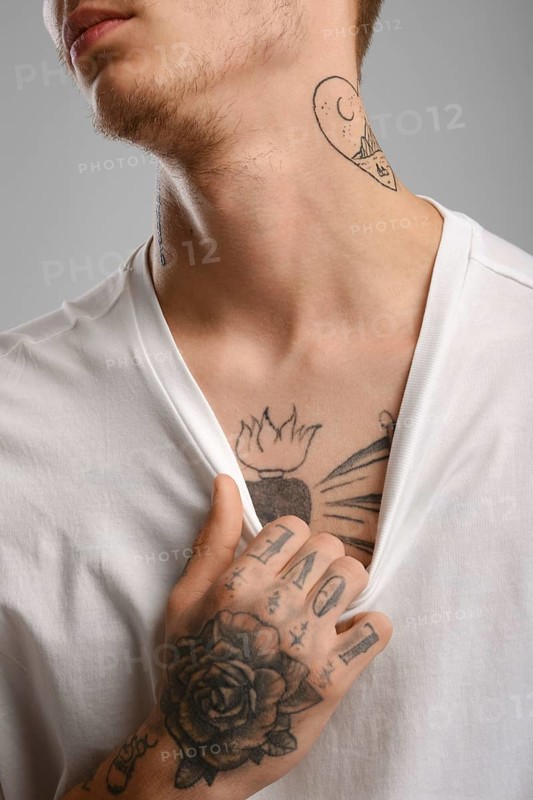 Cropped image of young tattooed man pulling his t-shirt
