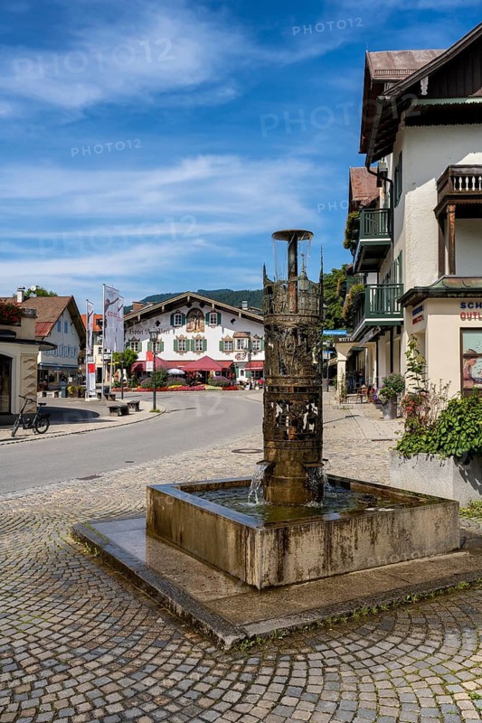 Bronze fountain with various Oberammergau themes in the centre of Oberammergau, district of Garmisch-Partenkirchen, Upper Bavaria, Germany, Europe