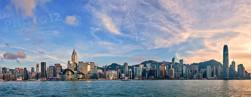 HONG KONG, CHINA, MAY 1, 2018: Panorama of Hong Kong skyline downtown skyscrapers over Victoria Harbour in evening with junk tourist ferry boat on sunset and dramatic sky. Hong Kong, China, Asia