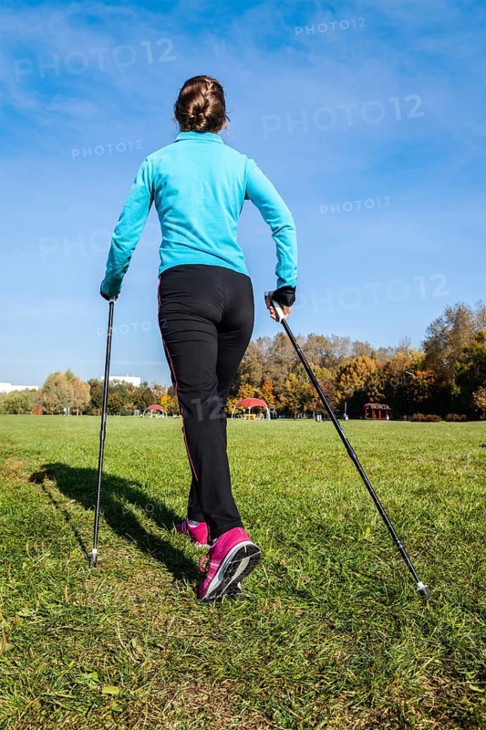 Nordic walking adventure and exercising concept, woman hiking withnordic walking poles in park