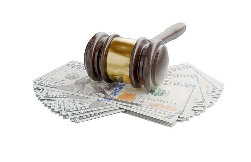Gavel resting on stacks of thousands of dollars isolated on a white background