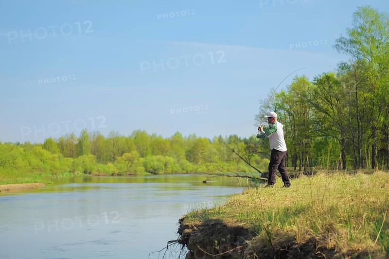 Fisherman throwing the bait with a spinning rod. Outdoor weekend activity. Photo with shallow depth of field taken at wide open aperture