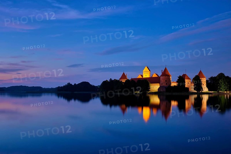 Evening view of Trakai Island Castle in lake Galve illuminated in the night reflecting in peaceful water, Lithuania, Europe