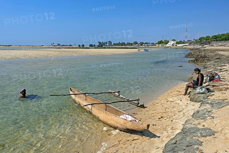 Single-outrigger canoe and two local Malagasy women on the beach at the coastal village Belo sur Mer, Morondava district, Menabe Region, Madagascar, Africa