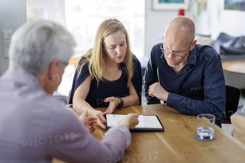 Symbolic photo on the subject of counselling. A young woman and a young man sit together at a table at home and receive counselling. Berlin, 13.08.2024
