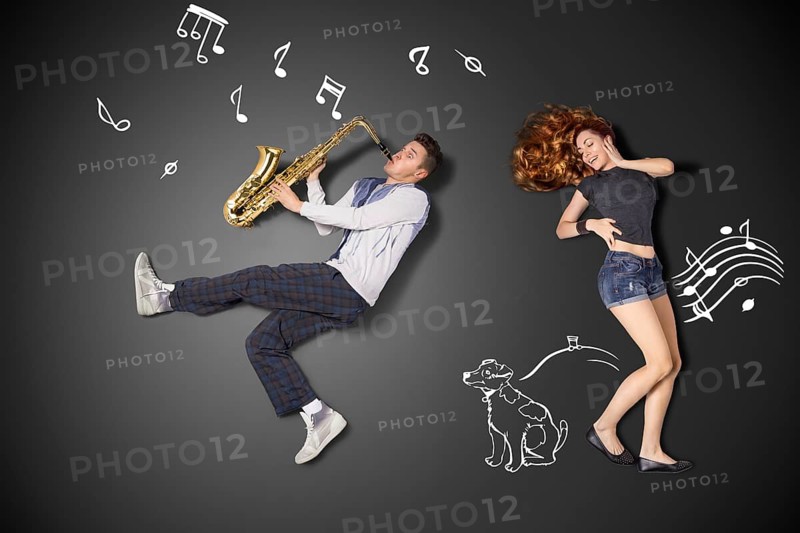 Happy valentines love story concept of a romantic couple against chalk drawings background. Male playing the saxophone for his girlfriend