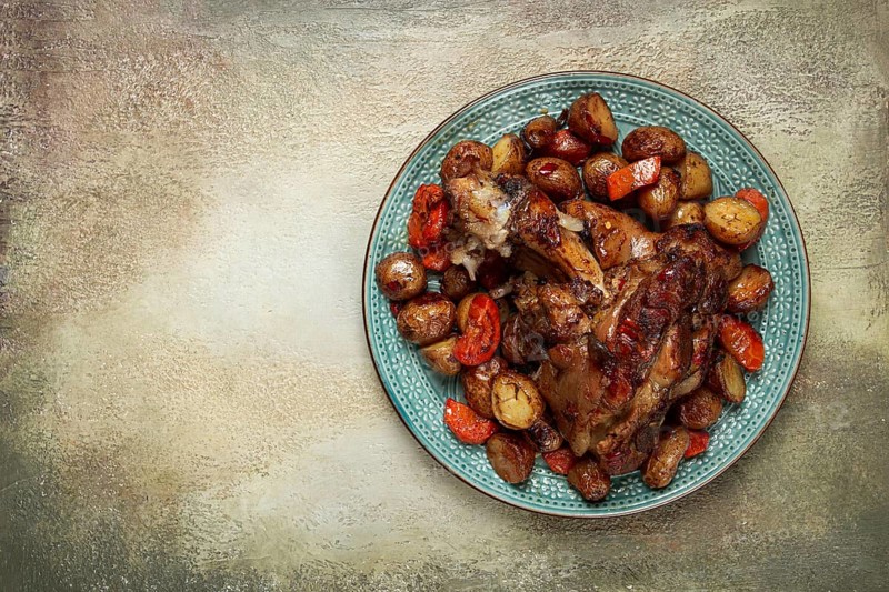 Pork knuckle baked with vegetables, new potatoes, on a plate, homemade, no people