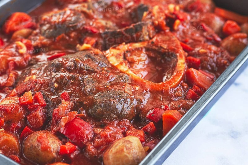 Ossobuco stew with vegetables, knuckle on the bone with new potatoes, in tomato sauce, homemade, top view, no people