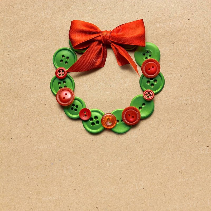 Creative concept photo of Christmas wreath made of buttons on a brown background