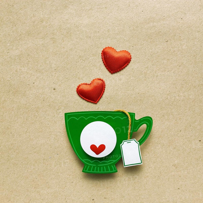 Creative valentines concept photo of a cup of tea with paper hearts on a brown background
