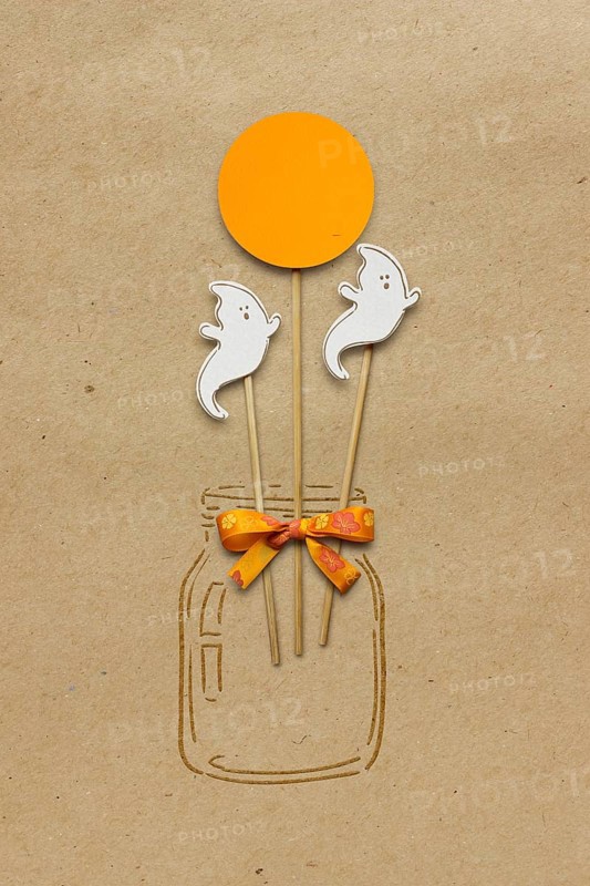Creative Halloween concept photo of a bottle with ghosts made of paper on a brown background