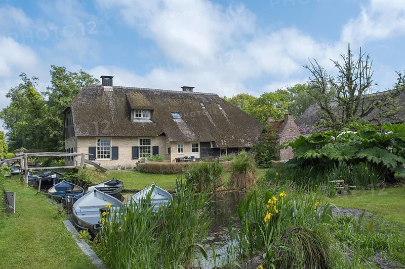 Farmstead with thatched roof, surrounded by river and pond full of boats in a green environment, Giethoorn, municipality of Steenwijkerland, province of Overijssel, Netherlands