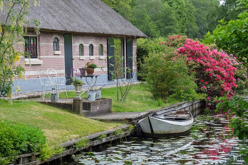 Cosy house on the canal with boat and flowering shrubs in an idyllic area, Giethoorn, municipality of Steenwijkerland, province of Overijssel, Netherlands