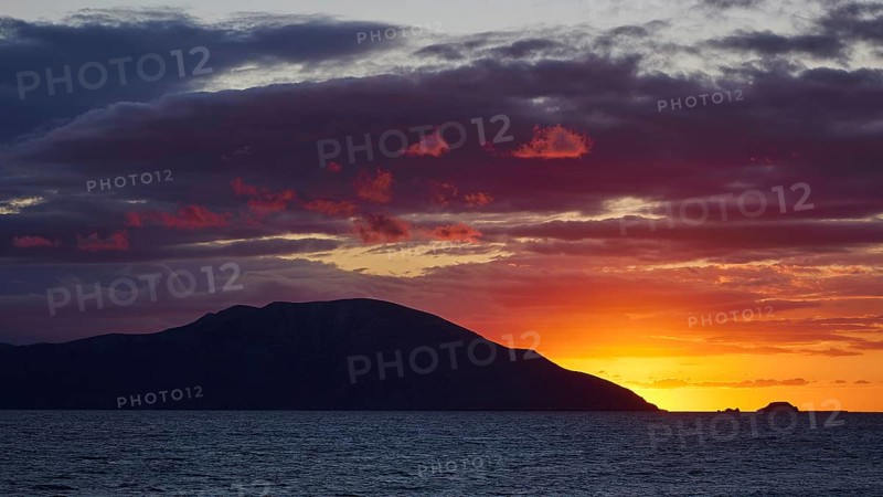 Sunset over the sea with an island in the background and a sky coloured in shades of orange and purple, sunset, Kassos, Karpathos, offshore islands, Dodecanese, Greek Islands, Greece, Europe