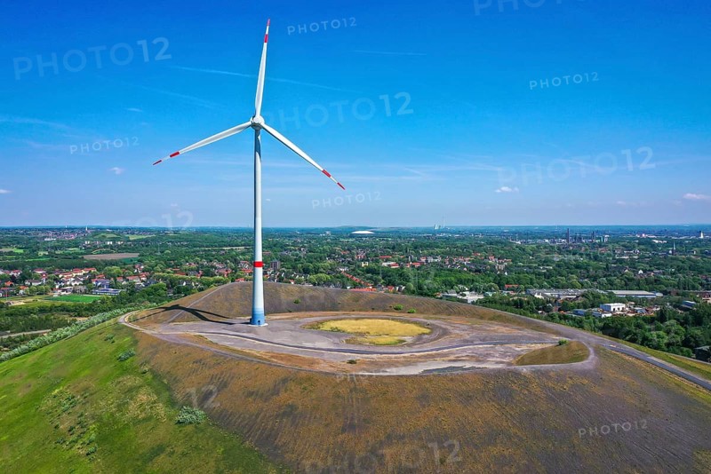 Gladbeck, Ruhr area, North Rhine-Westphalia, Germany, wind turbine on the Mottbruchhalde, a spoil tip in Gladbeck-Brauck. The hub height of the E-138 EP3 wind turbine manufactured by Enercon is 131 metres and the rotor diameter is 138.6 metres. When a rotor blade is positioned exactly vertically above the hub, the total height of the turbine is just under 200 metres. The operator is Gladbeck-Wind GmbH, a joint venture between STEAG and RWE. With an output of 3.5 megawatts (MW), the wind turbine produces around 10 million kilowatt hours (kWh) per year. In the background the Schalke Arena in Gelsenkirchen, Europe