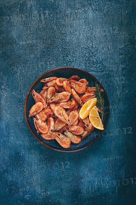 Fried shrimp, with shell and head, unpeeled, size 70-90, on a blue background, homemade, no people