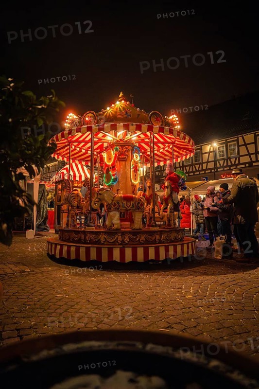 An illuminated carousel at a Christmas market surrounded by half-timbered houses at night, Christmas market Calw, Black Forest, Germany, Europe