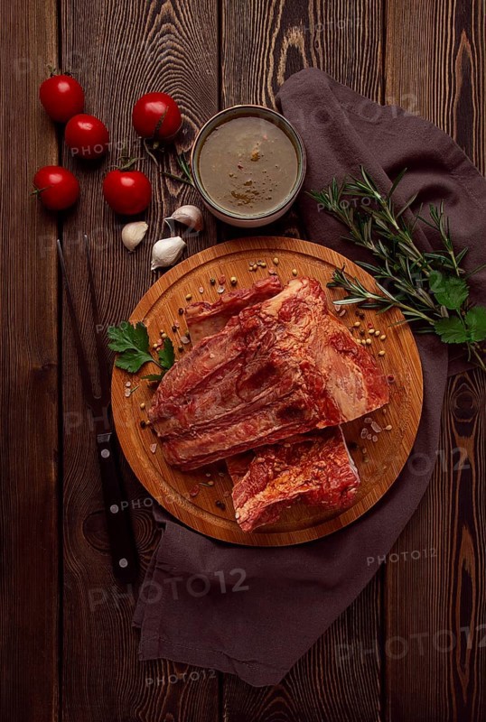 Smoked pork ribs, on a wooden table, top view, sauce, tomatoes and spices, close-up, vertical, no people