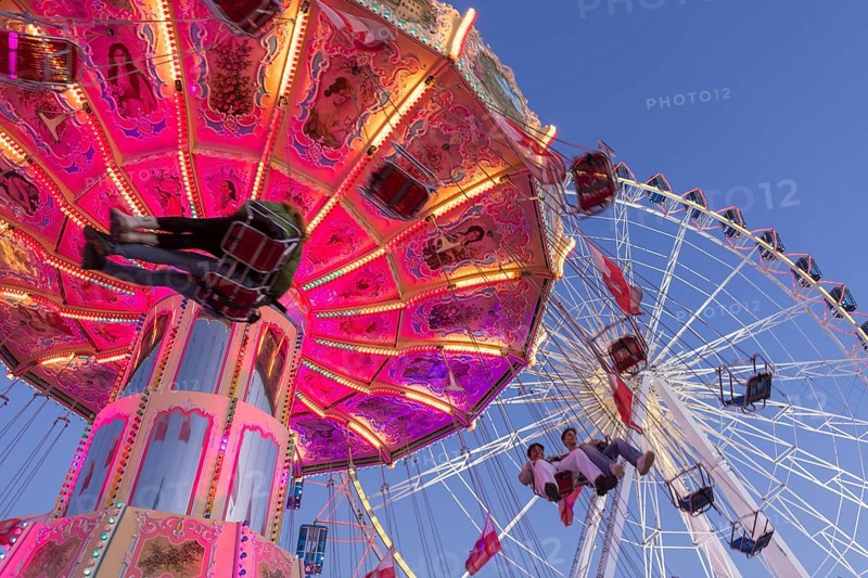 Illuminated chain carousel and Ferris wheel at night with cheerful people, funfair, wave flight, Cannstadter Volksfest, Stuttgart-Bad Cannstsdt, Baden-Württemberg