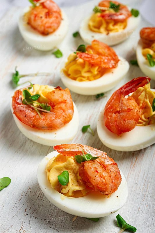 Boiled eggs stuffed with yolk and seasoned with mayonnaise, stuffed eggs with shrimp, on a white wooden chopping board, selective focus, close-up, without people