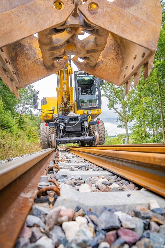 Excavator with shovel on railway tracks in a green environment, track construction, Hermann Hessebahn, Calw, Black Forest, Germany, Europe
