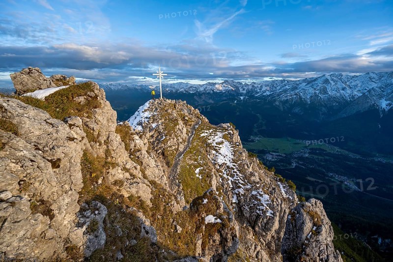 Mountaineer at the summit of the Kramerspitz with summit cross, at sunset, in autumn, Ammergau Alps, in autumn, Bavarian Alps, Bavaria, Germany, Europe