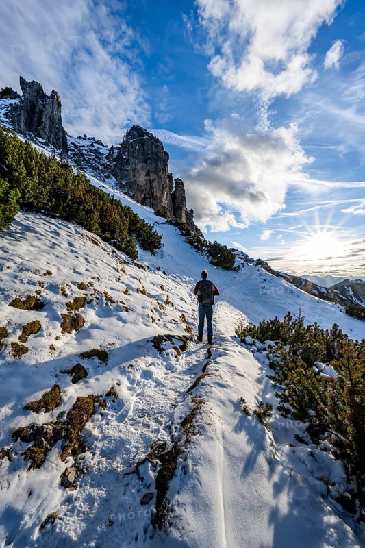 Hikers on a hiking trail with snow, sun star, ascent to Kramerspitz, in autumn, Ammergau Alps, Bavarian Prealps, Bavaria, Germany, Europe