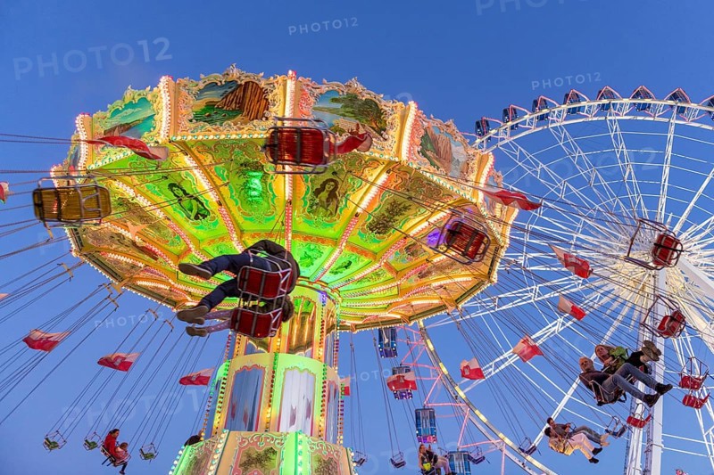 Illuminated chain carousel and Ferris wheel at night with cheerful people, funfair, wave flight, Cannstadter Volksfest, Stuttgart-Bad Cannstsdt, Baden-Württemberg