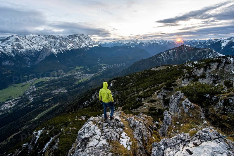 View Mountain panorama with Wetterstein mountains and Zugspitze, at sunset with sun star, mountaineer at the summit of the Kramerspitz, in autumn, Ammergau Alps, in autumn, Bavarian Prealps, Bavaria, Germany, Europe