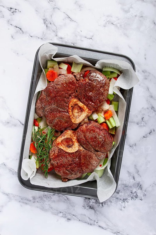 Fried meat on the bone, raw, chopped vegetables, ingredients in the oven, for cooking ossobuco, top view, no people