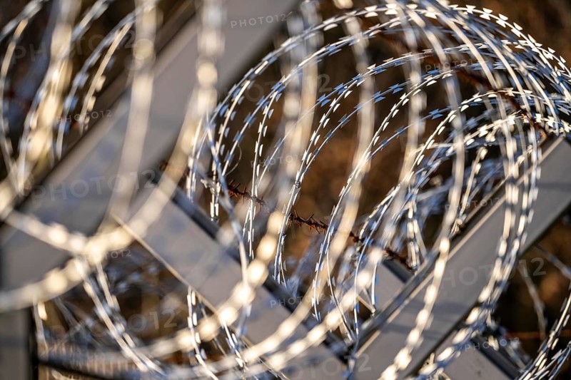 Symbolic image security, S-wire rolls, NATO wire, on a fence top, demarcation of a property, prevention of unauthorised access, strip steel wire with sharp blades