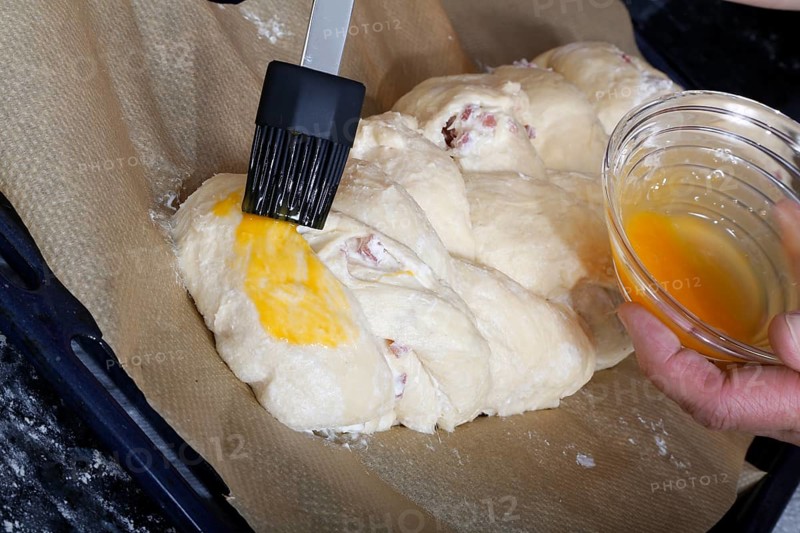 Swabian cuisine, preparation of savoury yeast plait with smoked meat, salty wreath bread, yeast yeast dough pastry, raw yeast dough with egg yolk, brush, grandmother's kitchen, regional, home cooking, typical Swabian cuisine reinterpreted, traditional cuisine reinterpreted, food photography, studio, Germany, Europe
