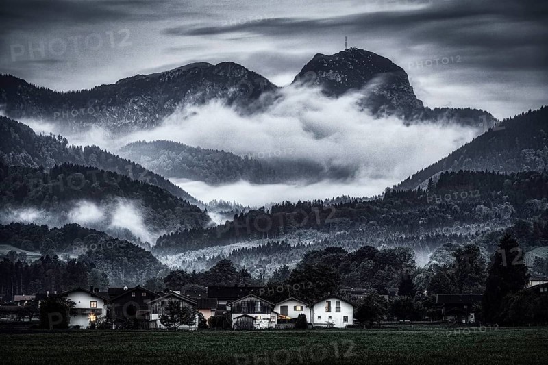 A dramatic landscape with mist-covered mountains, forests and a small village in the foreground, Wendelstein, Bad Feilnbach