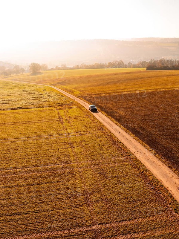 A car on a long dirt road, surrounded by vast golden fields in autumnal scenery, electric car VW ID5, Deer Carsharing, Gechingen, Black Forest, Germany, Europe