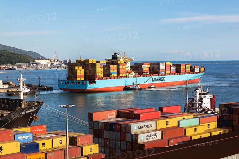 Maersk Serangoon cargo ship loaded with metal box shipping containers being guided by pilot boats into La Spezia cargo Port, Italy, Europe