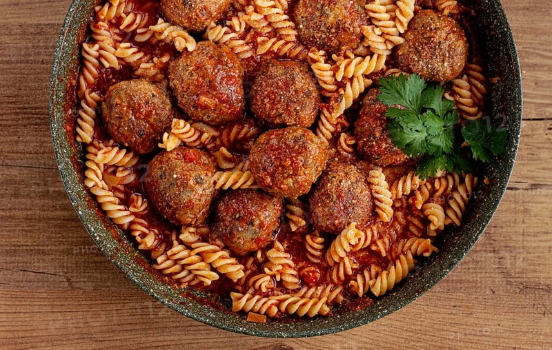 Minced meat meatballs, in tomato sauce, with fusilli pasta, in a cast-iron pan, homemade, no people