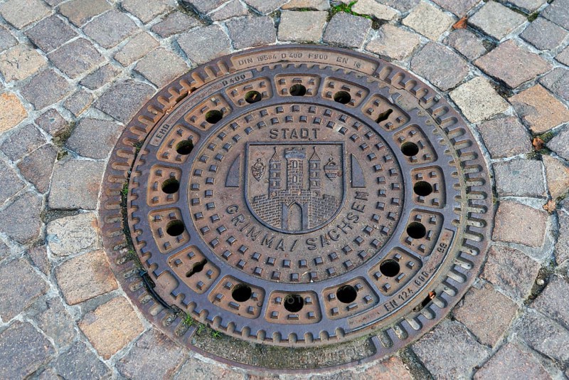 Round manhole cover with city coat of arms, surrounded by cobblestones, manhole cover, manhole cover, Grimma, Leipzig, Saxony, Germany, Europe