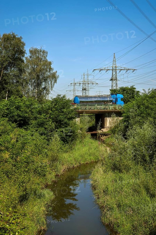 Bottrop, North Rhine-Westphalia, Germany, Renaturalised Boye, the tributary of the Emscher, was transformed into a near-natural watercourse, flood protection through newly designed floodplains, the Boye is now free of wastewater after the construction of a parallel sewer, is part of the Emscher river system and thus part of the Emscher conversion, was previously an open, above-ground wastewater canal, mixed water canal with surface water and wastewater. Car traffic on the B224 federal road bridge at the back, Europe