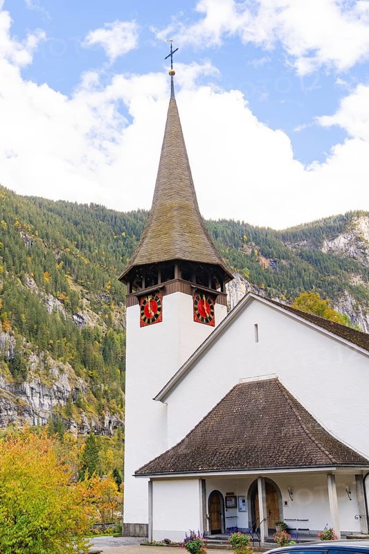 Small church with characteristic tower against an autumnal wooded mountain backdrop, Lauterbrunnen, Switzerland, Europe