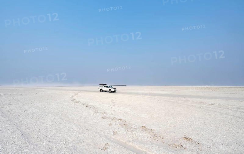 Four-wheel drive Toyota Hilux with roof tent, driving over salt pan, lone car in large wide plain, Nxai Pan National Park, Botswana, Africa