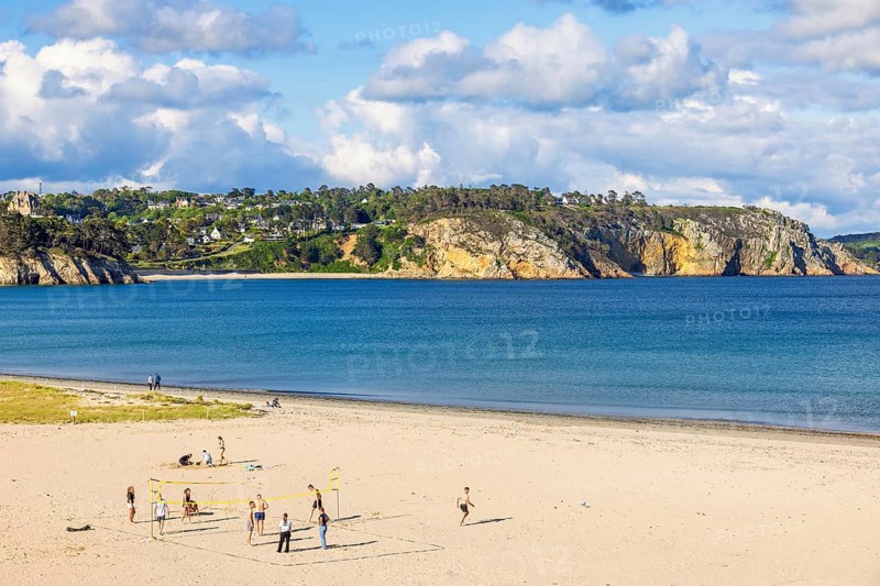 Young people playing volleyball on the sandy beach by the sea on a sunny summer day, Crozon peninsula, Morgat, Bretagne, France, Europe