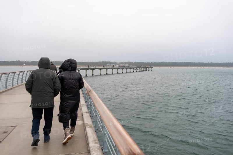 A couple walks along the new pier in rainy weather, Prerow, Mecklenburg-Vorpommern, Germany, Europe