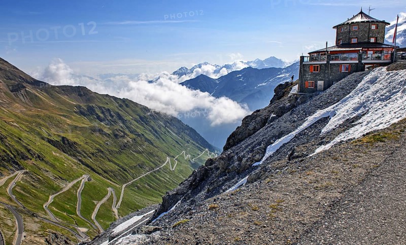 View to the left steep mountain wall with 2758 metres high highest pass road in Italy with narrow serpentines hairpin bends mountain road alpine pass Stelvio Stelvio, on the right historic hotel restaurant Tibet House, Stelvio, South Tyrol, Alto Adige, Italy, Europe