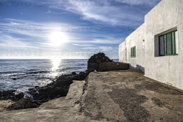 White house with green shutters on the coast with sea and sky in the background, Canary Islands, Lanzarote, Spain, Europe