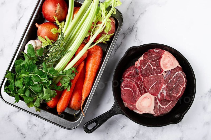 Sknuckle on the bone, raw meat for ossobuco, in a cast-iron pan, baking sheet with vegetables, top view, no people