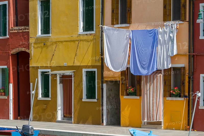 Laundry hangs on a yellow façade, the Mediterranean style creates a cosy atmosphere, Burano, Venice, Italy, Europe