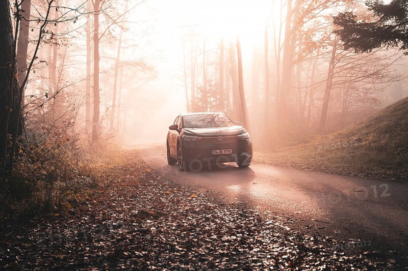 A car on a foggy road in autumn forest with golden sunlight in the morning, electric car VW ID5, Deer Carsharing, Gechingen, Black Forest, Germany, Europe
